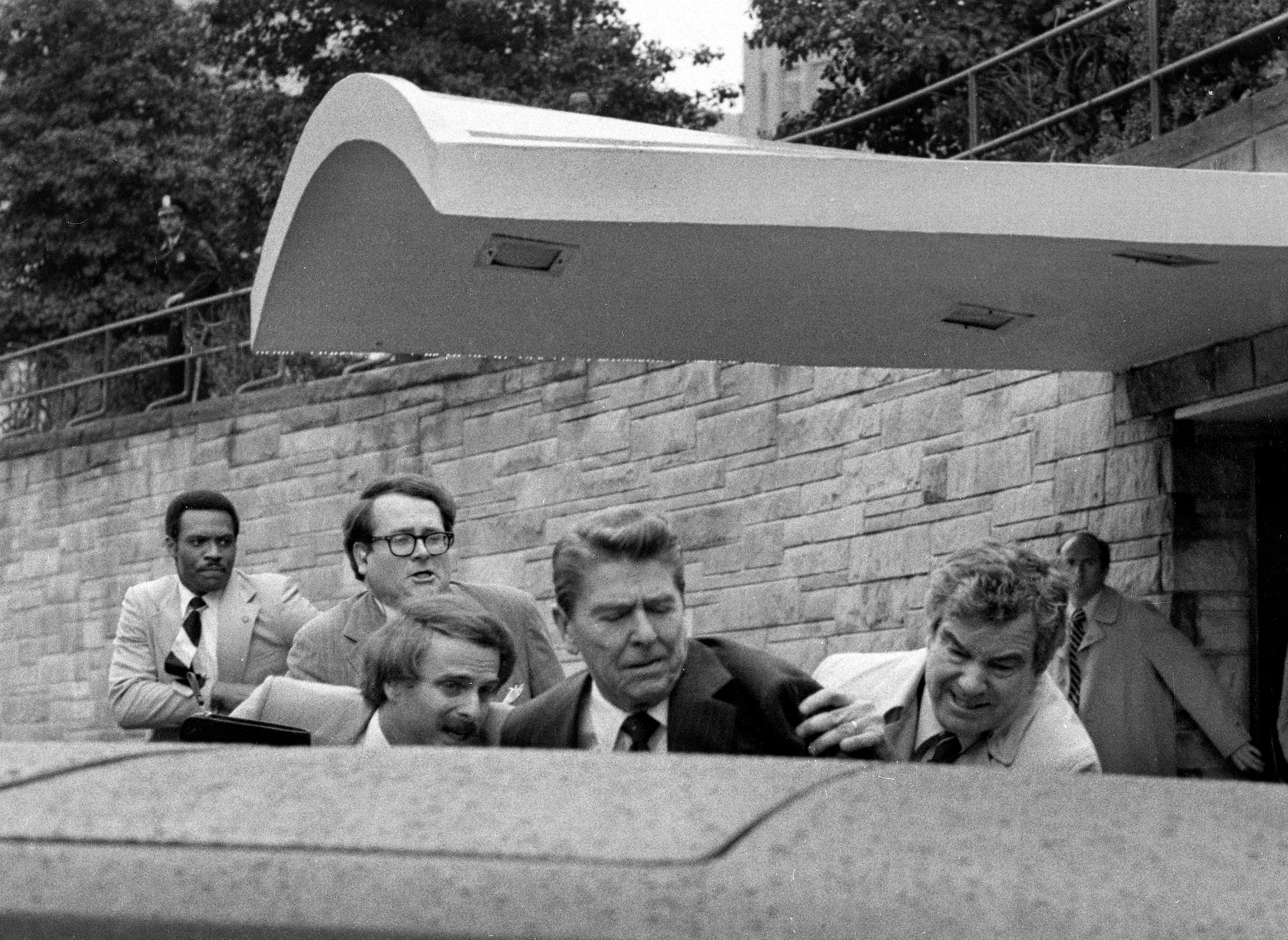 U.S. President Ronald Reagan winces and raises his left arm as he was shot by an assailant as he left a Washington hotel, Monday, March 30, 1981, after making a speech to a labor group. The President was shot in the upper left side. (AP Photo/Ron Edmonds)