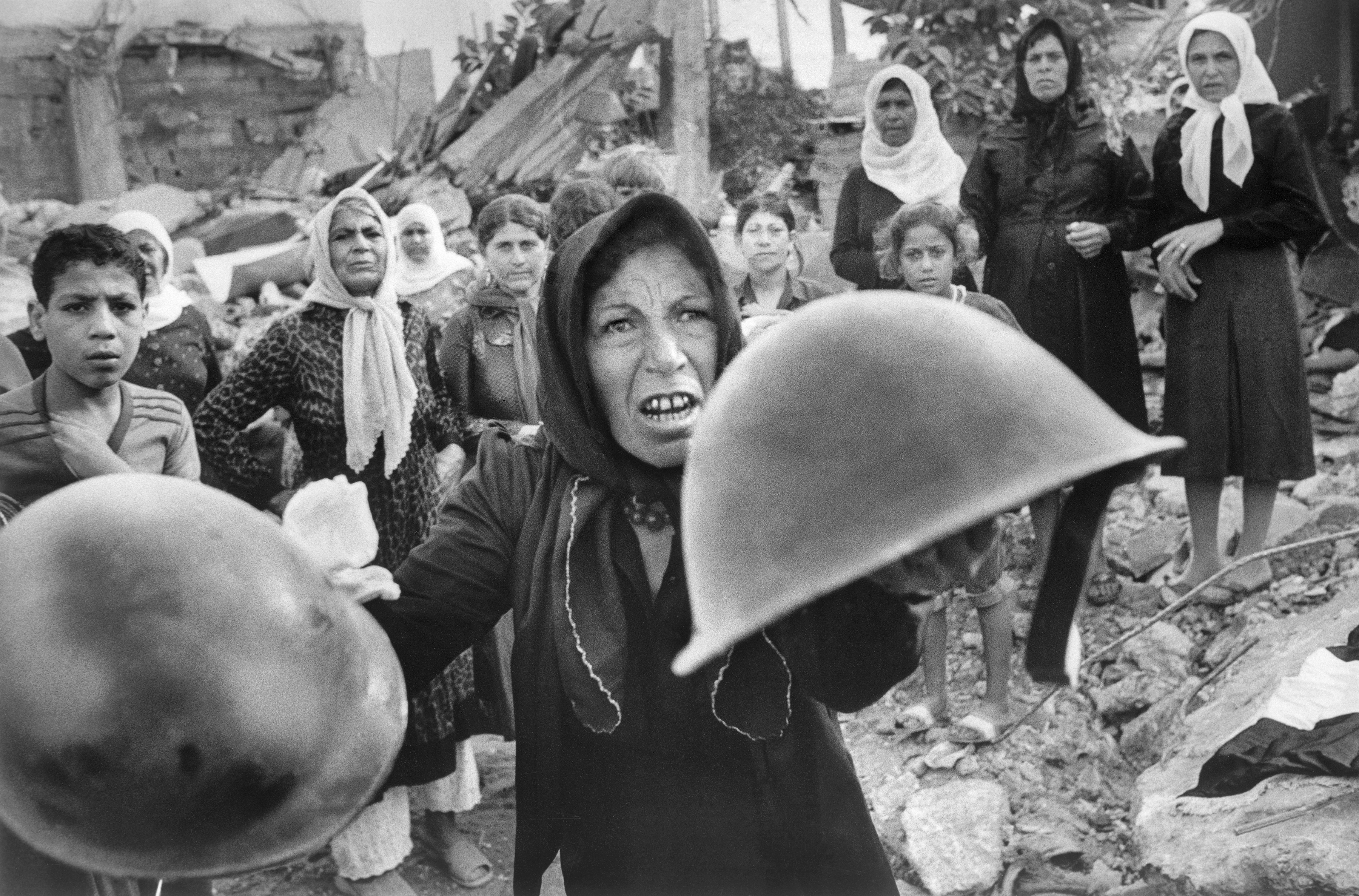 A Palestinian woman brandishes helmets during a memorial service in Beirut September 27, 1982, for victims of Lebanon's Sabra refugee camp massacre. She claimed the helmets ere worn by those who massacred hundreds of her countrymen. (AP Photo/Bill Foley)