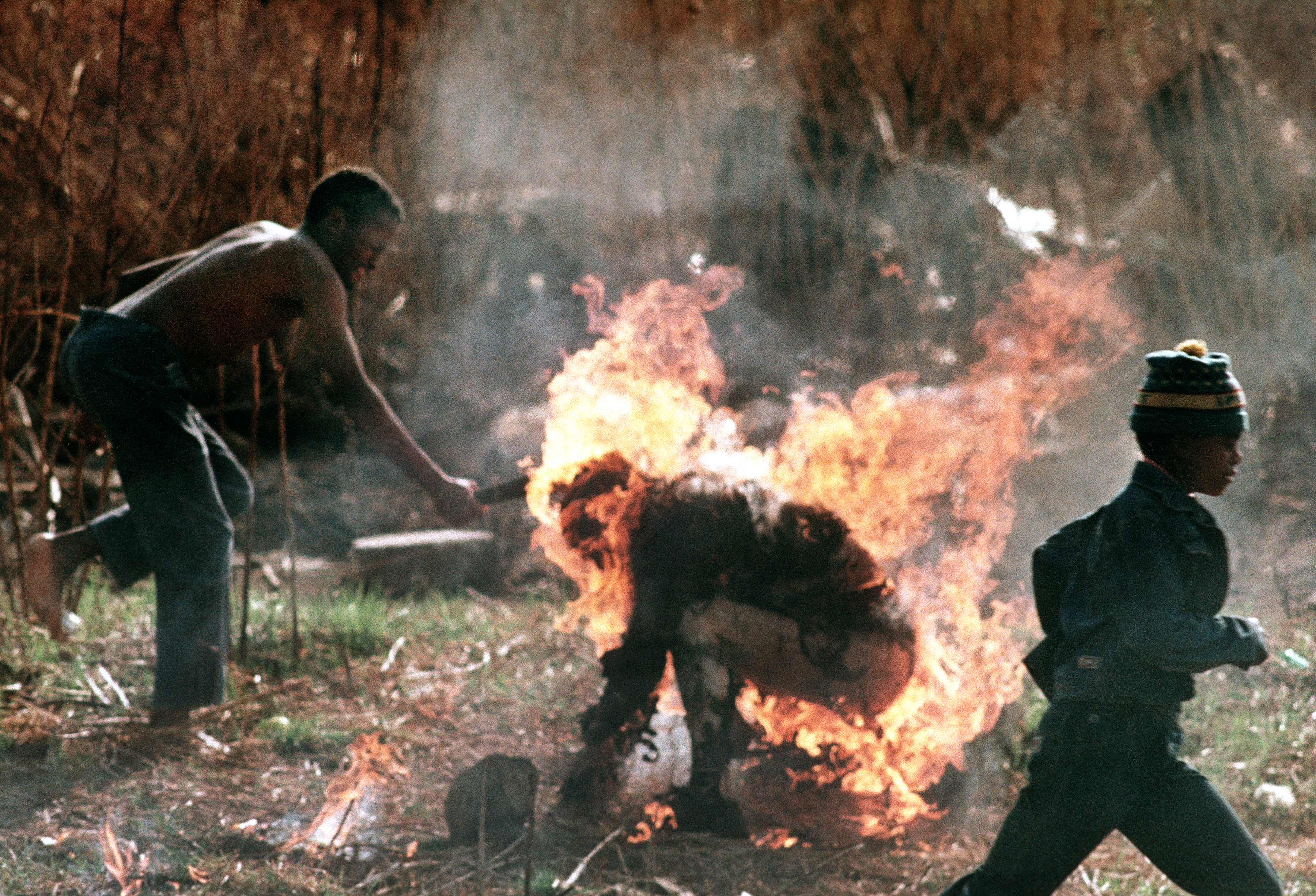 The burning body of a man identified as a Zulu Inkatha supporter is clubbed by a follower of the rival African National Congress during factional violence in Soweto, South Africa, on Sept. 15, 1990. (AP Photo/Greg Marinovich)