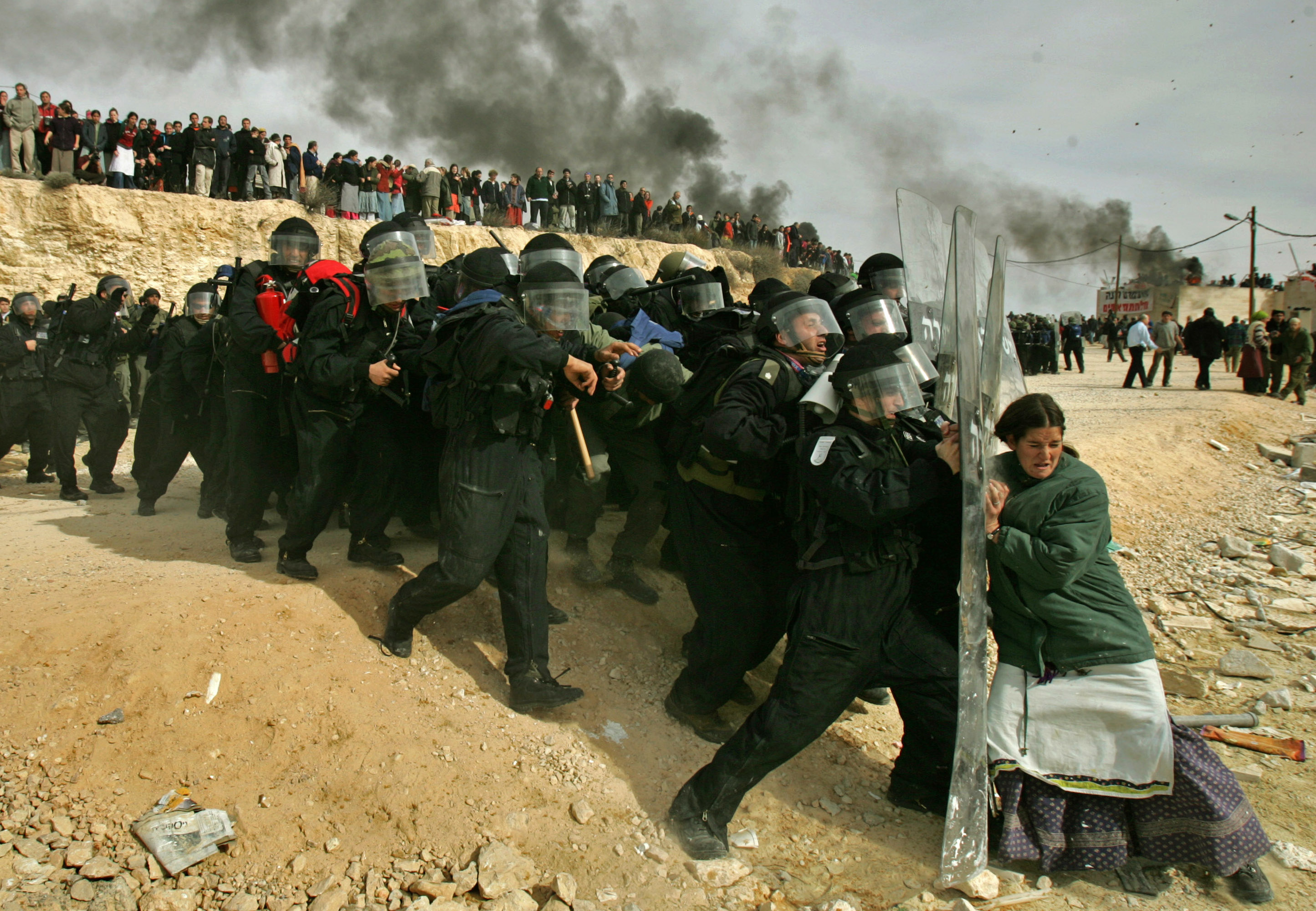 A lone Jewish settler challenges Israeli security officers during clashes that erupted as authorities cleared the West Bank settlement of Amona, east of the Palestinian town of Ramallah, Feb. 1, 2006. Thousands of troops in riot gear and on horseback clashed with hundreds of stone-throwing Jewish settlers holed up in this illegal West Bank outpost after Israel’s Supreme Court cleared the way for demolition of nine homes at the site. (AP Photo/Oded Balilty)