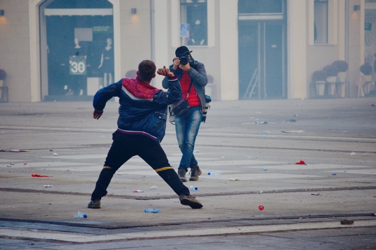 Photographer taking picture of rioter throwing an object