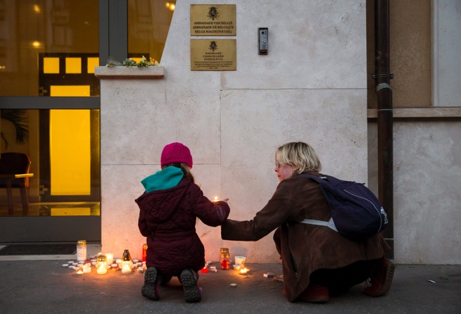 Woman and child lighting candles on a sidewalk
