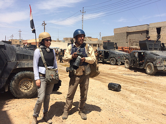 Journalists in protective vests working on a road in Iraq